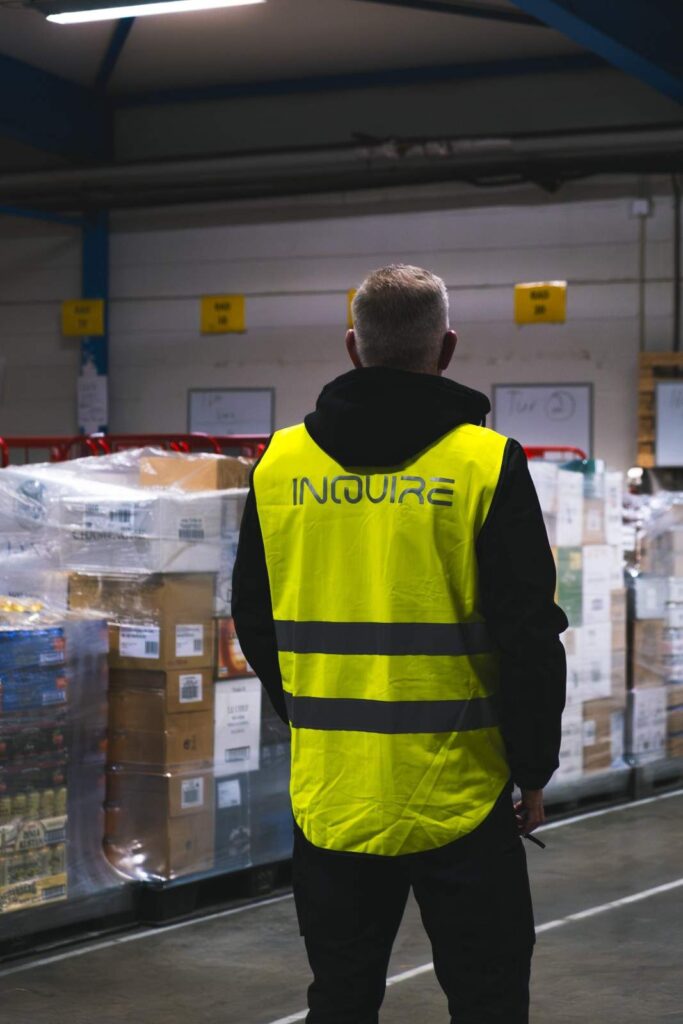Medarbetare i InQuire-varselväst i lager med pallat gods
