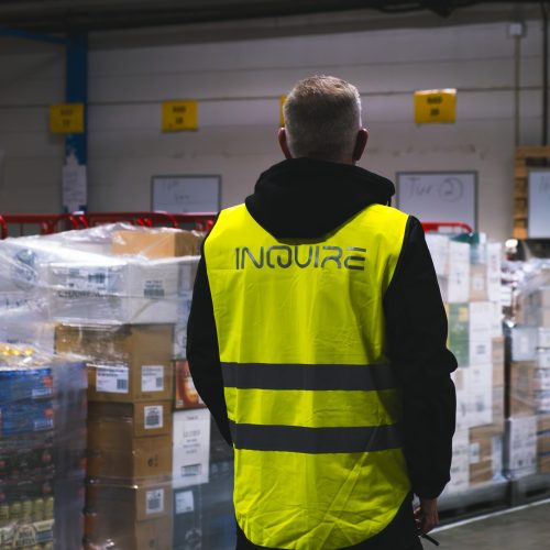 Medarbetare i InQuire-varselväst i lager med pallat gods